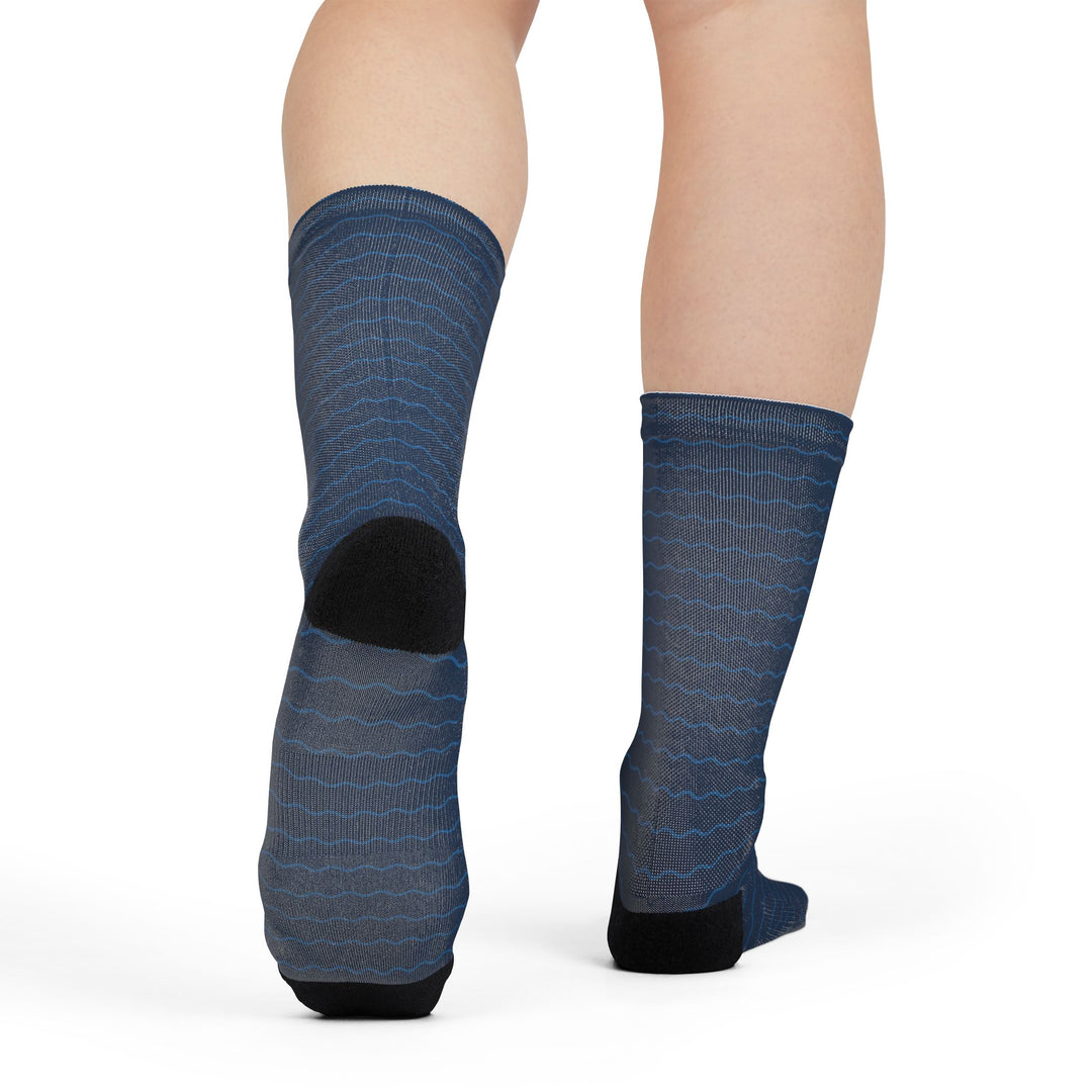 Rear view of a model in navy wave nautical crew socks lifting one foot to show the black heel