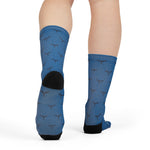 Rear view of a model in blue Whale Hello There novelty crew socks with black heels and whale tail print