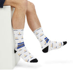 Close-up of feet in white nautical crew socks with gold anchors, blue ribbons and black toes, seated pose