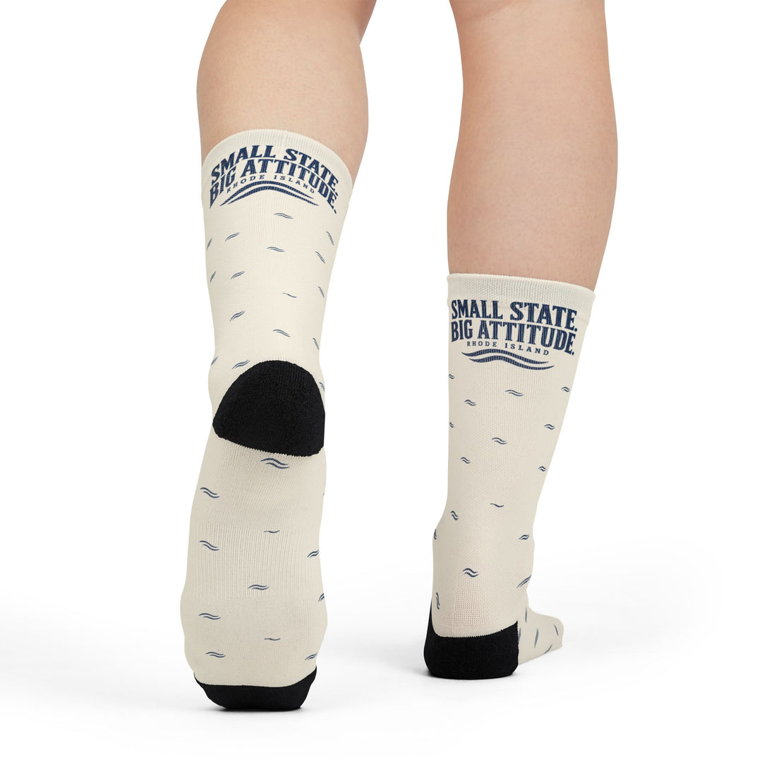 Model mid-step from behind showing the black heel of white Small State. Big Attitude. Rhode Island gift socks