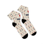 Folded pair of tan Nautical But Nice tattoo anchor socks with black heels, toes and navy anchor print