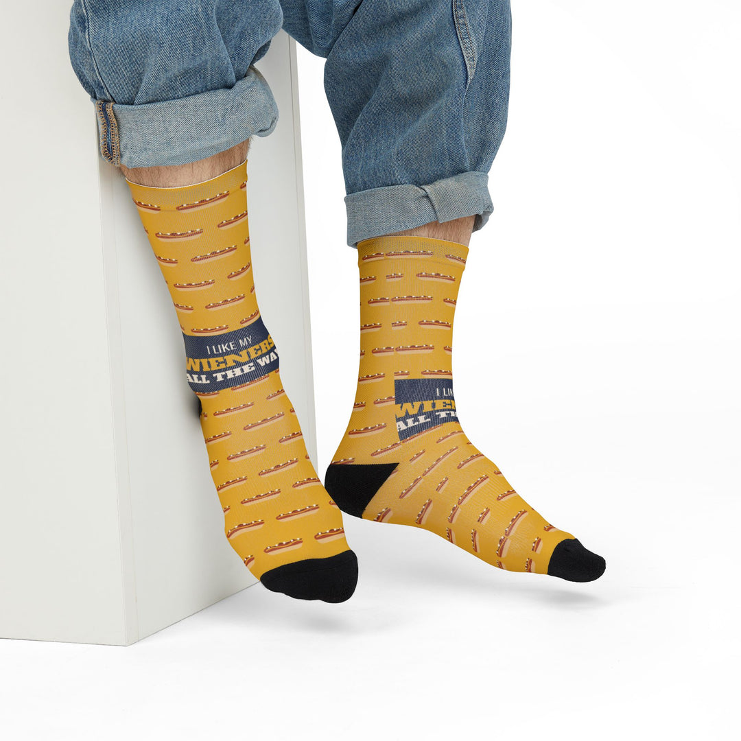 Model in rolled jeans seated on a white block wearing mustard yellow Rhode Island hot wiener socks