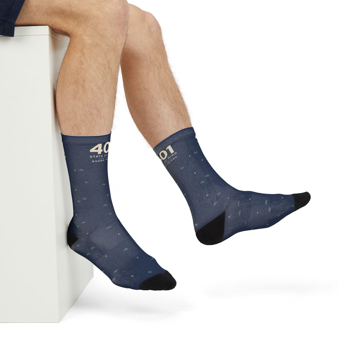 Close side view of raised feet in navy 401 State of Mind Rhode Island socks with black heels and toes