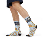 Side view of a model walking in light blue Rhode Island socks printed with stuffed quahogs and lemon
