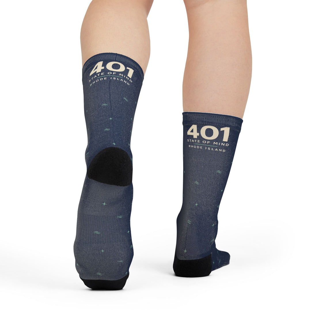 Model mid-step from behind showing the black heel of navy 401 State of Mind Rhode Island gift socks