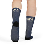 Model mid-step from behind showing the black heel of navy 401 State of Mind Rhode Island gift socks