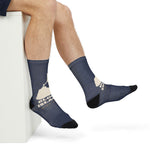 Seated model crossing ankles in navy Rhode Island socks with the Block Island outline print