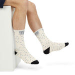 Crossed legs in One More Crossing Block Island gift socks showing navy and teal wave pattern, side view