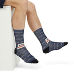 Seated with legs crossed in Are We There Yet? Block Island socks, navy ferry print and black toes