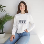 Woman seated beside a potted plant in the white One More Crossing Block Island sweatshirt with waves