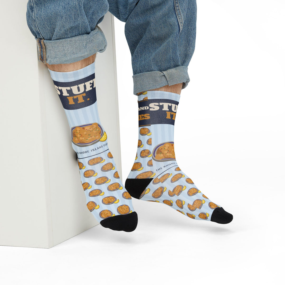 Model in jeans seated on a white block wearing Stuff It. funny beach socks with a stuffed quahog plate