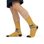Model mid-stride in denim shorts wearing mustard yellow hot wiener socks with navy slogan band
