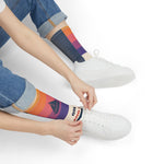 Seated model in rolled jeans tying a white sneaker while wearing On Island Time nautical crew socks