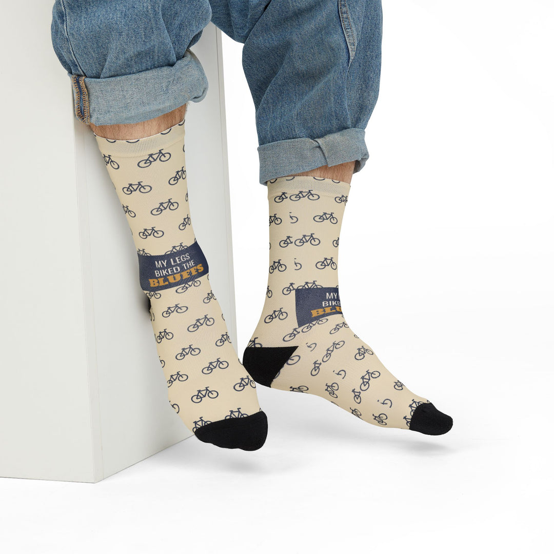 Model in rolled jeans seated on a white block wearing cream My Legs Biked the Bluffs crew socks