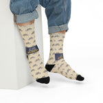 Model in rolled jeans seated on a white block wearing cream My Legs Biked the Bluffs crew socks