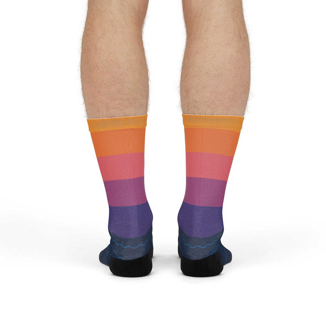 Front view of model standing in orange, pink and purple sunset sailboat crew socks fading to navy