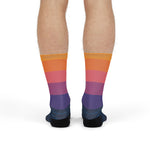 Front view of model standing in orange, pink and purple sunset sailboat crew socks fading to navy