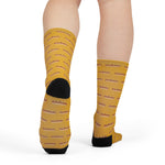 Rear view of model in mustard yellow funny Rhode Island crew socks with hot wiener print and black heels