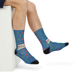 Seated model with crossed legs in blue Rhode Island boater socks printed with red and green buoys