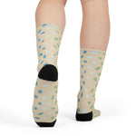 Rear view on a model of sand sea glass socks showing black heels and blue and green glass pattern