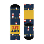 Flat lay of navy Get Lit funny beach socks showing the lighthouse print, yellow band and black toes