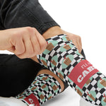 Tight close-up of a hand tugging a checkered sock up the shin, coral I'll Have a Cabinet band on Rhode Island socks