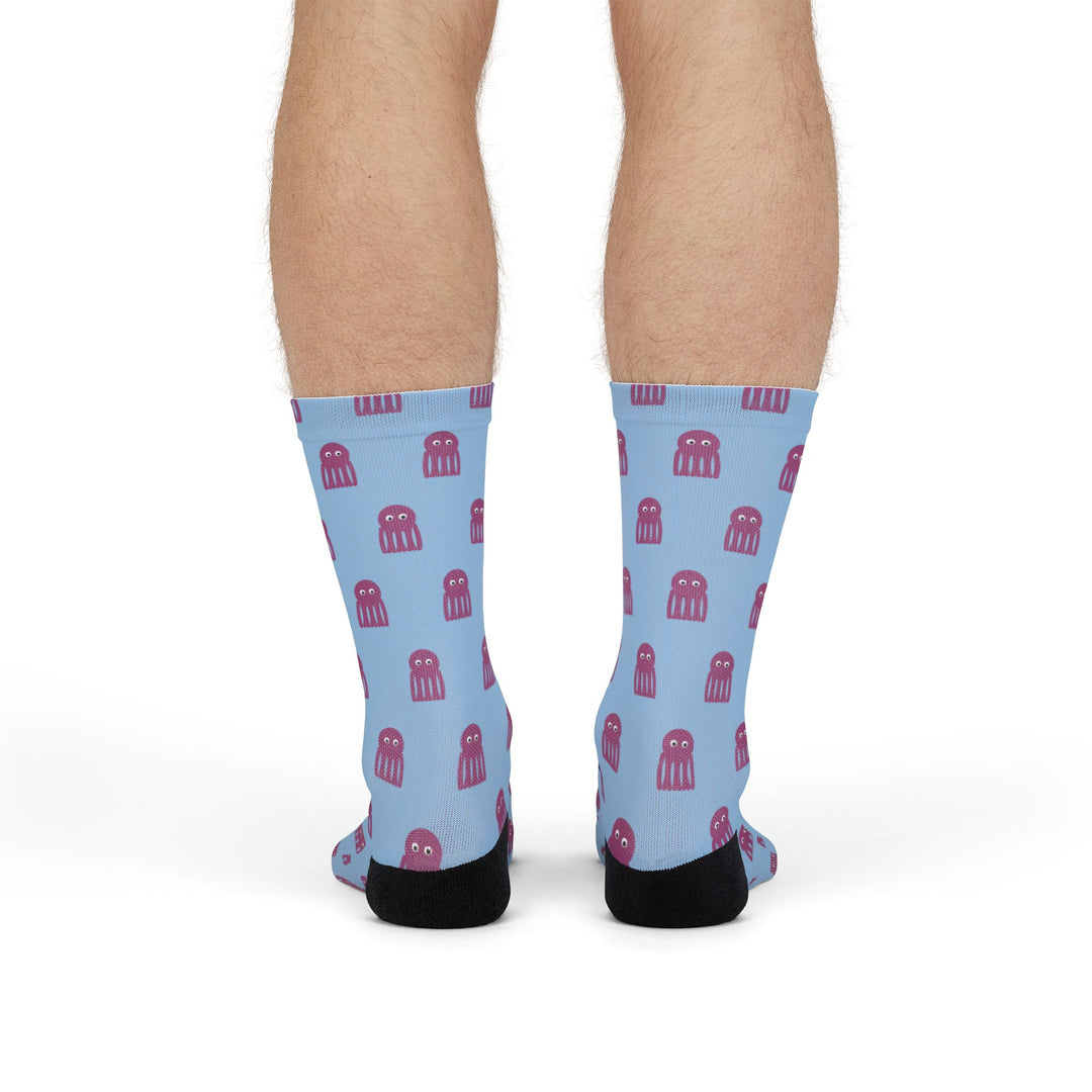 Front view on standing model of light blue funny beach socks covered in pink octopuses