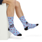Seated model stretching one foot out in light blue funny ocean crew socks with pink octopuses