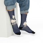 Seated model in rolled jeans showing the cream island outline on navy Block Island crew socks