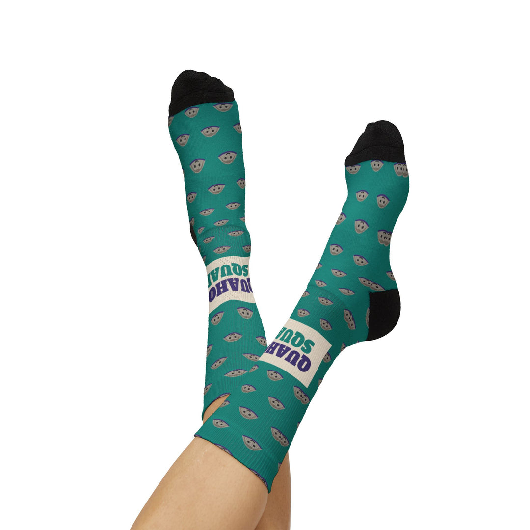 Raised crossed legs in teal Quahog Squad clam socks, black heels up and the cream Quahog Squad band on one ankle