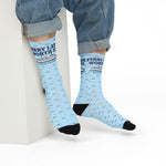 Seated model in rolled jeans showing Ferry Late. Worth It. Block Island crew socks with ferry and navy dots