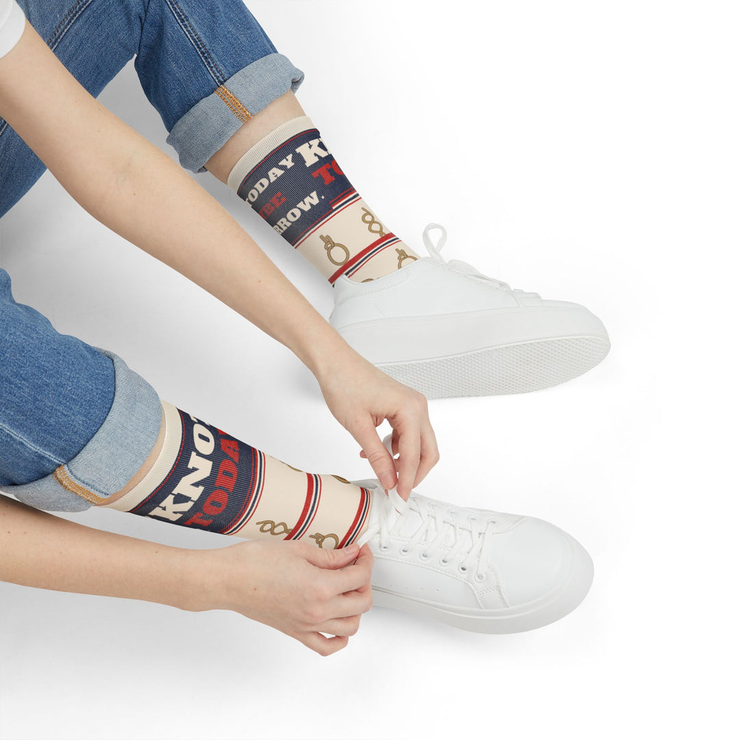 Seated model tying a white sneaker while wearing retro Knot Today rope knot nautical crew socks