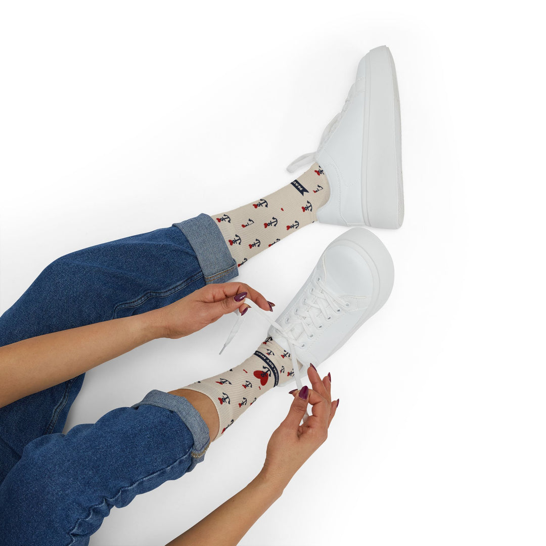 Seated model lacing white sneakers over tan Nautical But Nice retro sailor socks with anchor print