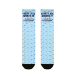 Ferry Late. Worth It. Block Island socks laid flat: light blue crew socks with navy ferry graphic and black heel and toe