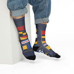 Model in rolled jeans seated on a white block wearing BLOCK ISLAND nautical flag crew socks