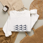 Cozy flat lay of the white One More Crossing crewneck with candle and wicker basket, a Block Island gift