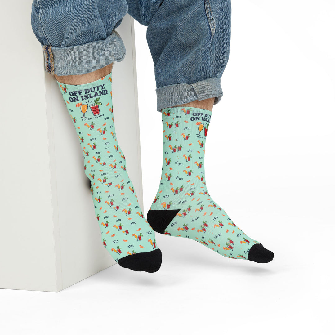 Model in rolled jeans seated on a white block wearing Off Duty. On Island. Block Island gift socks