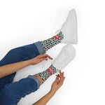 Seated model in jeans and white sneakers showing I'll Have a Cabinet funny beach socks at the ankle, coral band visible