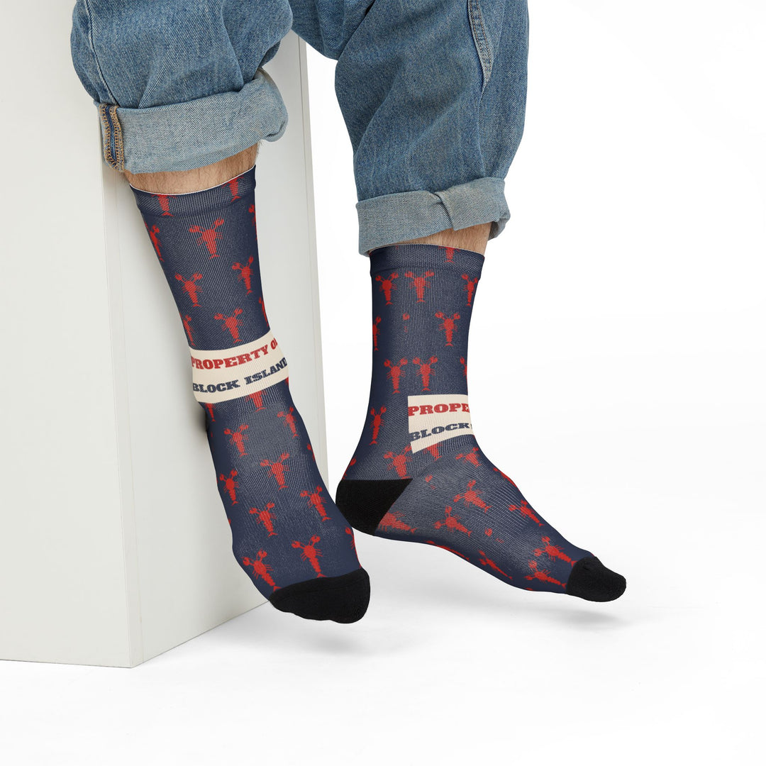 Model in rolled jeans seated on a white block wearing Property of Block Island lobster Rhode Island socks