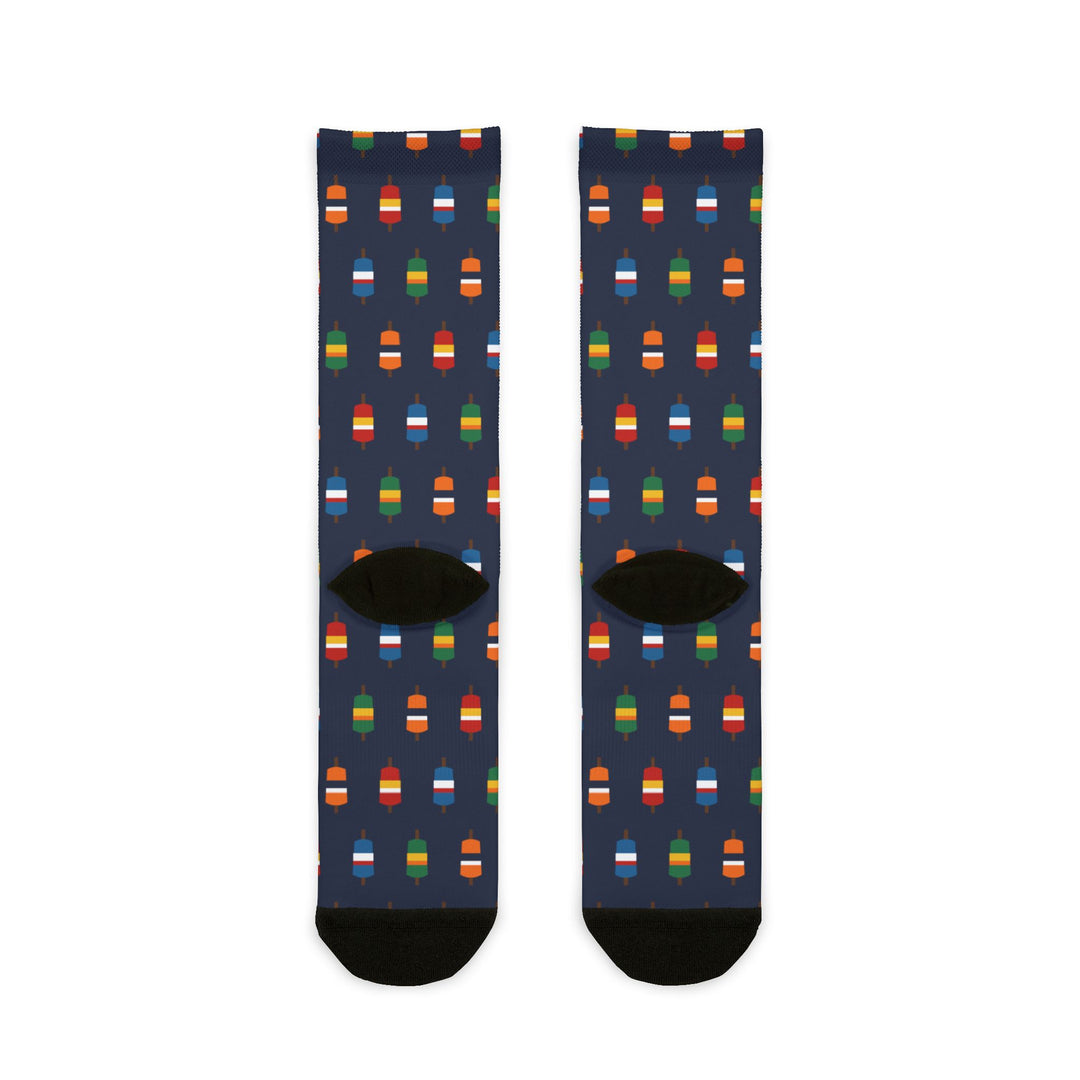 Back of navy Nice Buoys crew socks showing the multicolor lobster buoy pattern and black heels, flat lay