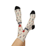 Bare legs crossed in the air wearing tan Nautical But Nice tattoo anchor socks with navy banner