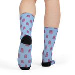 Rear view on legs of light blue octopus crew socks with black heel and rows of pink octopuses