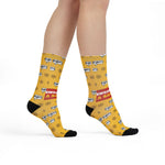 Model walking in yellow Swear Like a Sailor crew socks with #@!% bubbles, ship wheels and black toes, side view