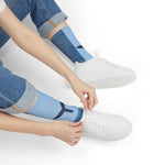 Person in jeans tying white sneakers while wearing blue Whale Hello There ocean socks