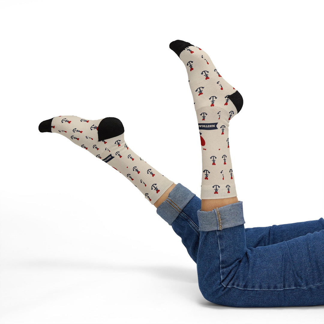 Reclining model in jeans with legs raised showing tan nautical crew socks with anchors and red hearts