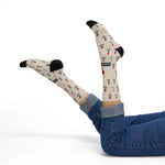 Reclining model in jeans with legs raised showing tan nautical crew socks with anchors and red hearts