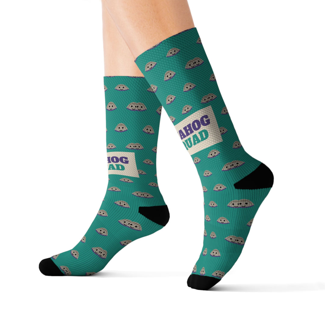 Size S Quahog Squad funny beach socks on leg forms mid-stride, teal with tan clam shells and a purple-lettered band