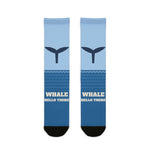 Whale Hello There socks laid flat: light-to-deep blue ocean socks with a navy whale tail and black heel and toe
