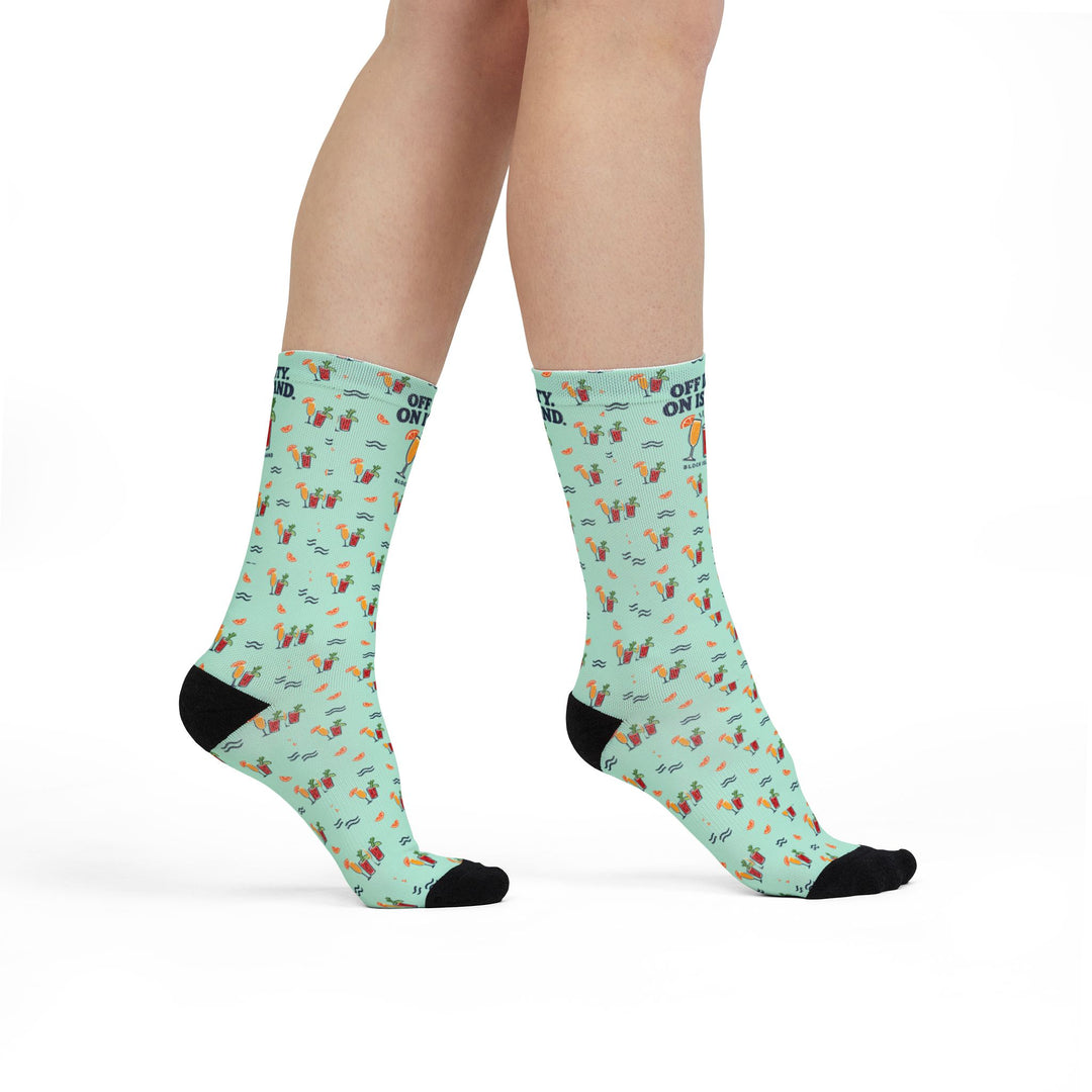 Model standing in mint green Off Duty. On Island. funny beach socks with cocktail print, side view