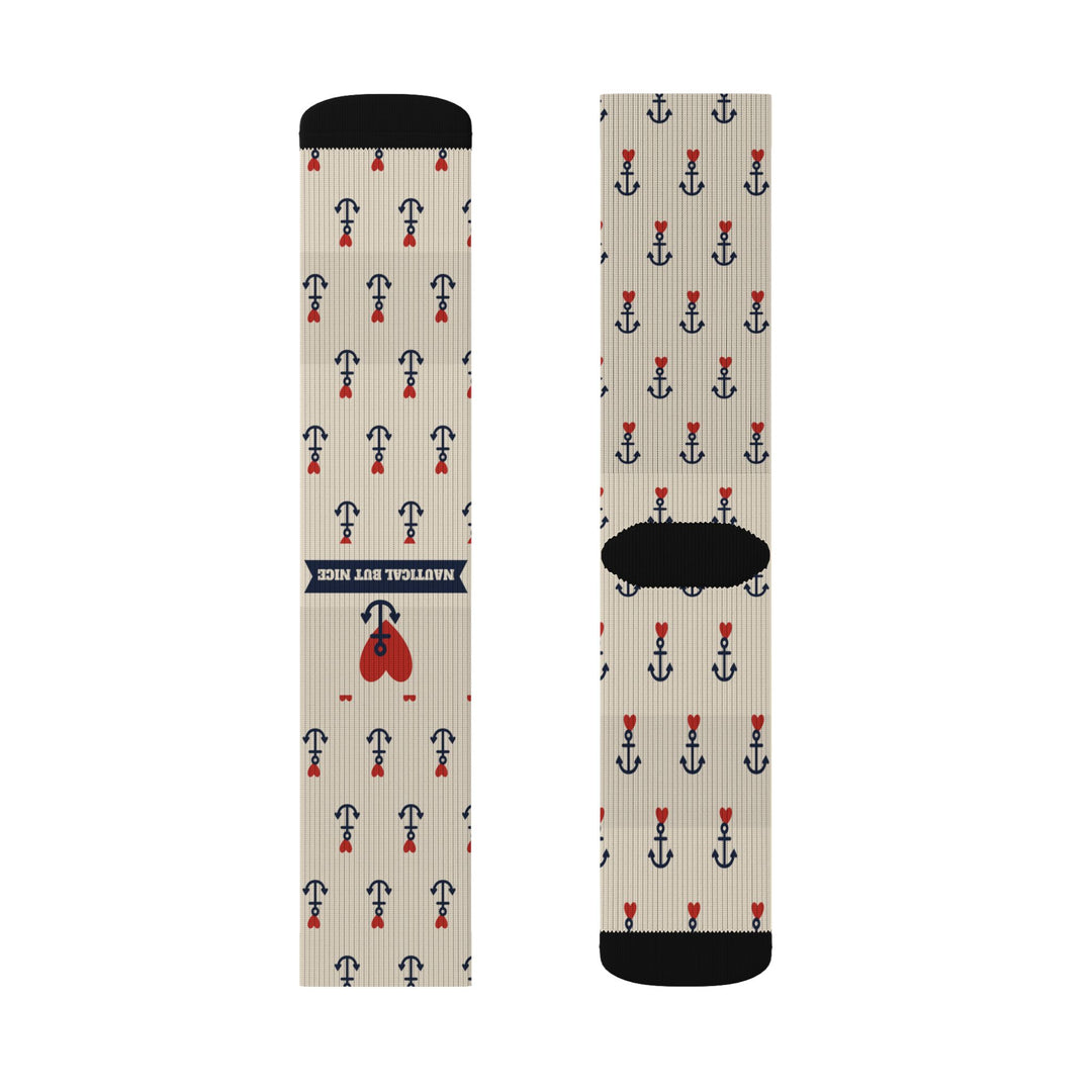 Flat lay of tan nautical crew socks, front with navy Nautical But Nice banner and heart, back with black heel